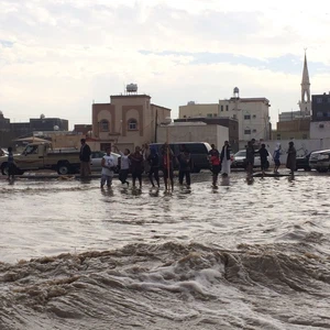 طلاب يلهون في السيول خارج أسوار المدرسة 