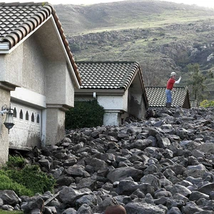 عامل يقف فوق الصخور بعد أن غطت المنازل