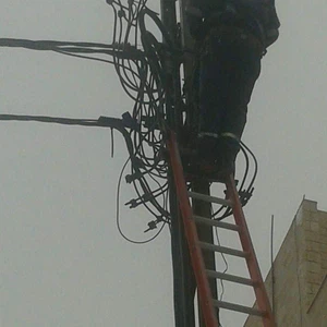 أحد العمال يصعد على عمود الكهرباء من أجل اصلاح الأعطال فيه 