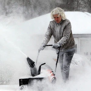 أمريكية تحاول إزالة الثلوج عن مدخل المنزل