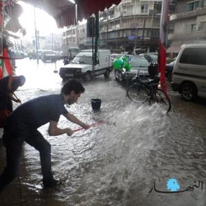 صاحب محل تجاري في شمال لبنان يحاول منع المياه من مداهمة المحل - جريدة النهار