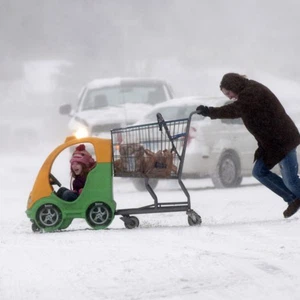 امرأة تدفع ابنتها وسط هبوب الرياح الثلجية القاسية