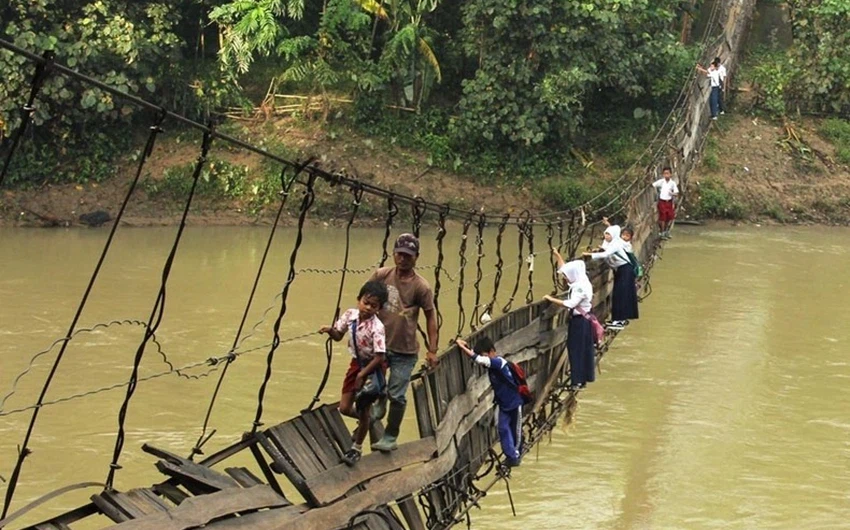 التلاميذ يمرون عبر جسر معلق ومهترئ في اندونيسيا