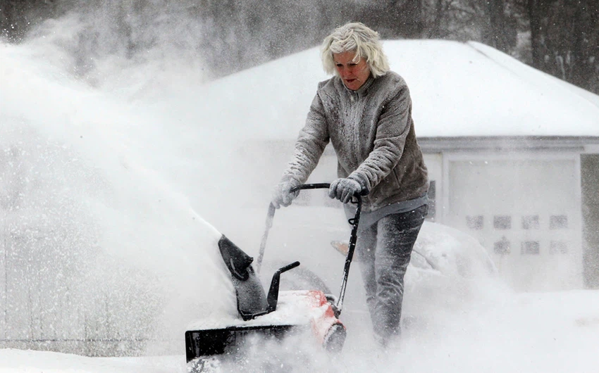 أمريكية تحاول إزالة الثلوج عن مدخل المنزل
