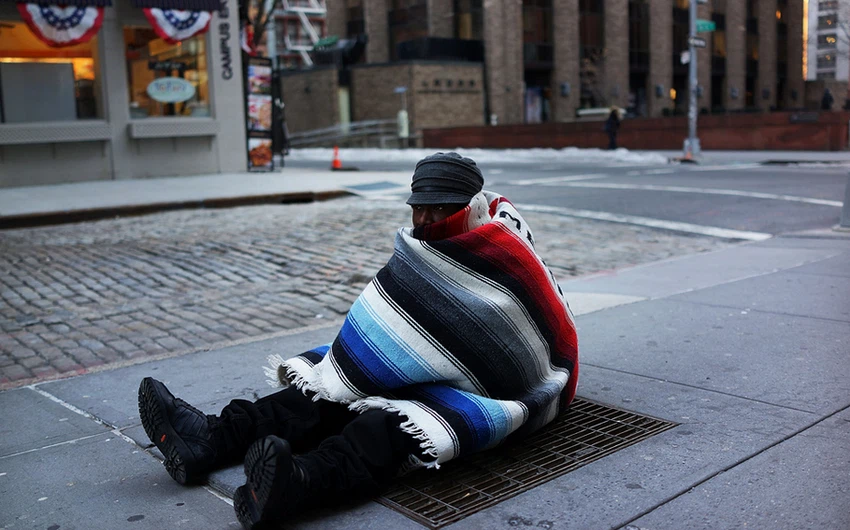 مشرد بلا مأوى يعاني صامداً في وجه البرد القارس