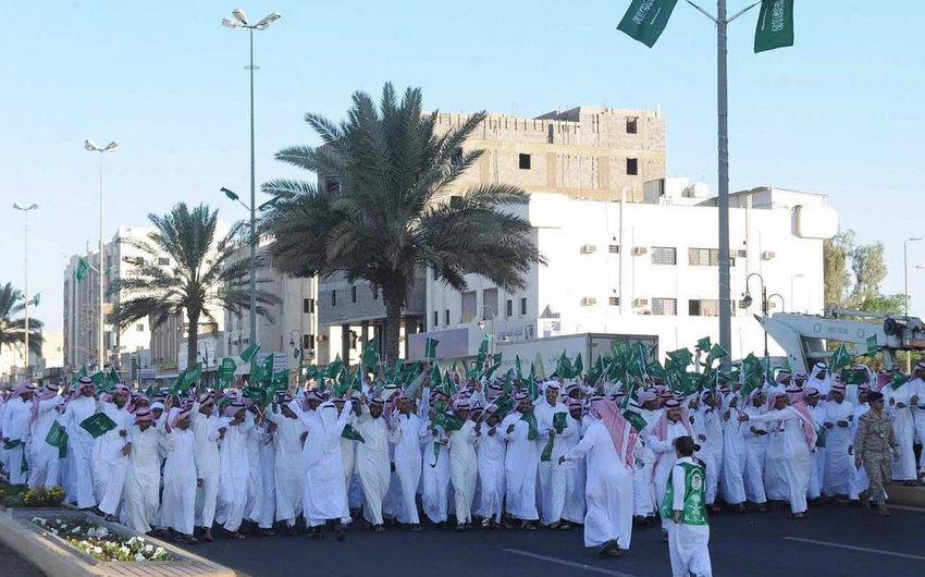 مسيرة للشباب يرفعون خلالها العلم السعودي