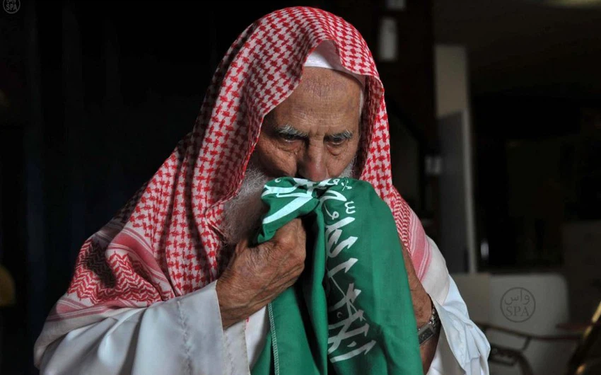 صورة معمر سعودي يقبل العلم 