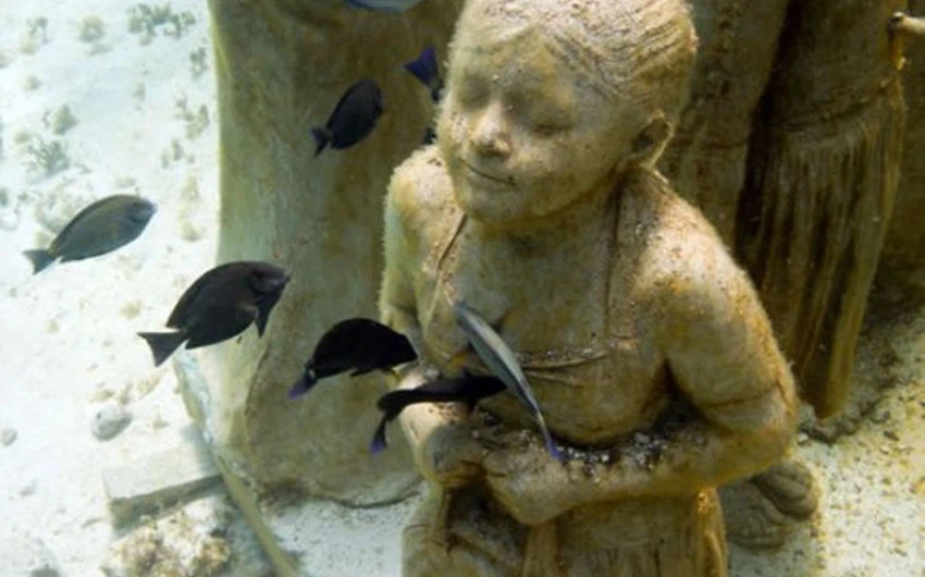 تمثال لطفل صغير بين الاسماك 